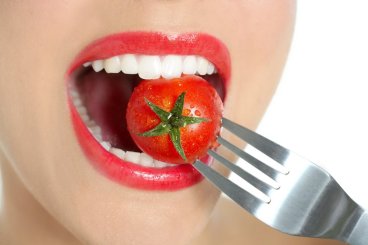 Eating a red tomato macro of woman teeth and red lips mouth